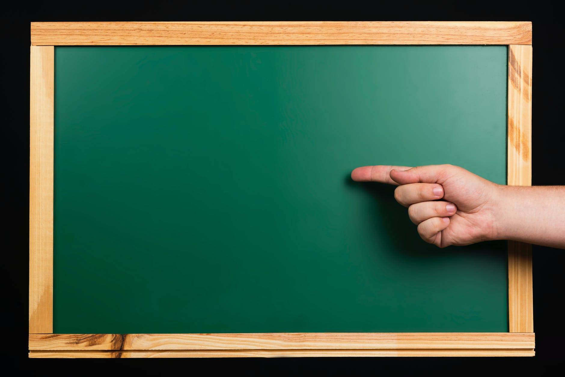 persons hand on green board